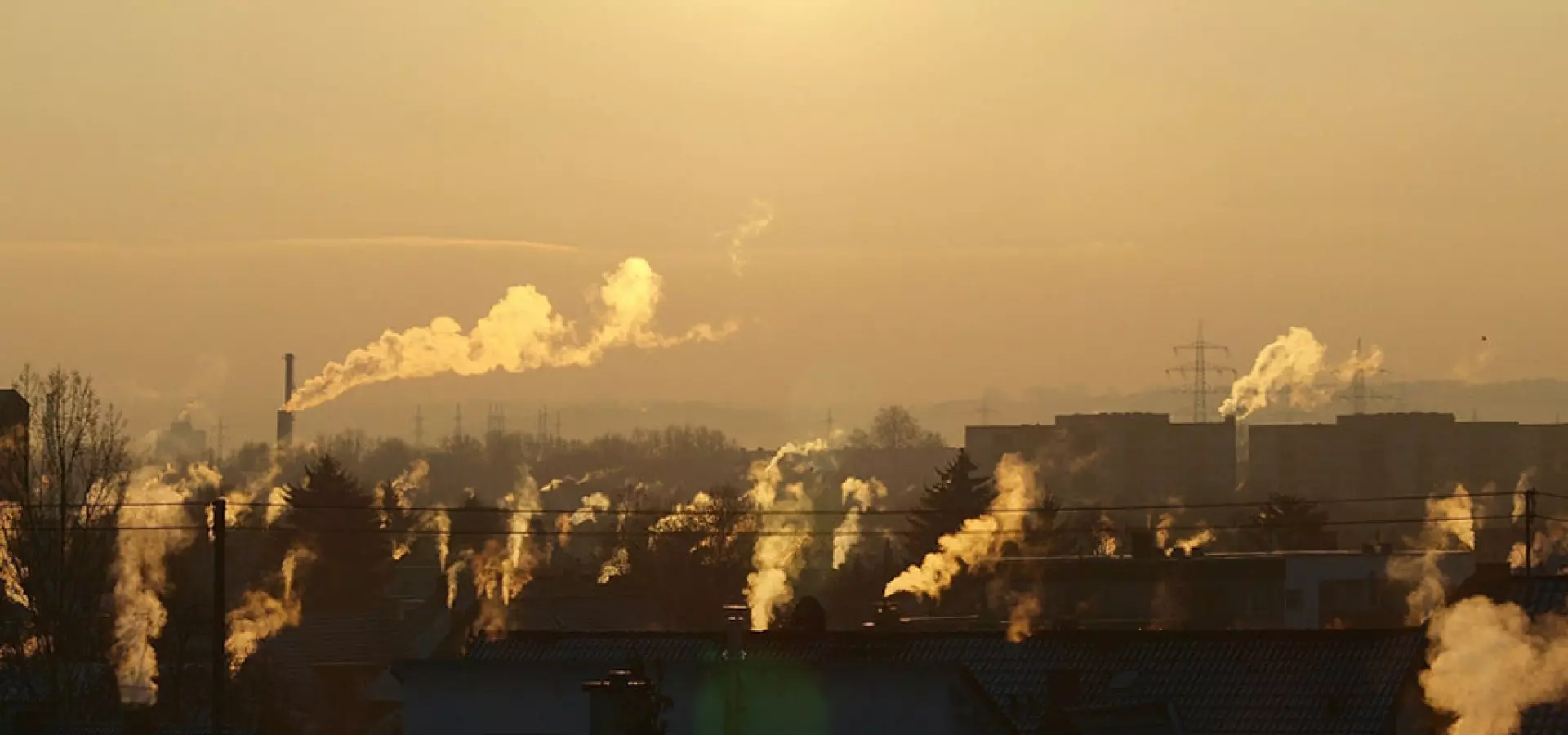 Luftverschmutzung, Smog, Industrie, Schornsteine, Rauchfahnen, Sonnenaufgang/-untergang, Stadtlandschaft, Dunst Städtische Skyline im gelblichen Dunst: Über vielen Schornsteinen steigen weiße Rauchfahnen auf, die tief stehende Sonne steht in einem smogigen Himmel