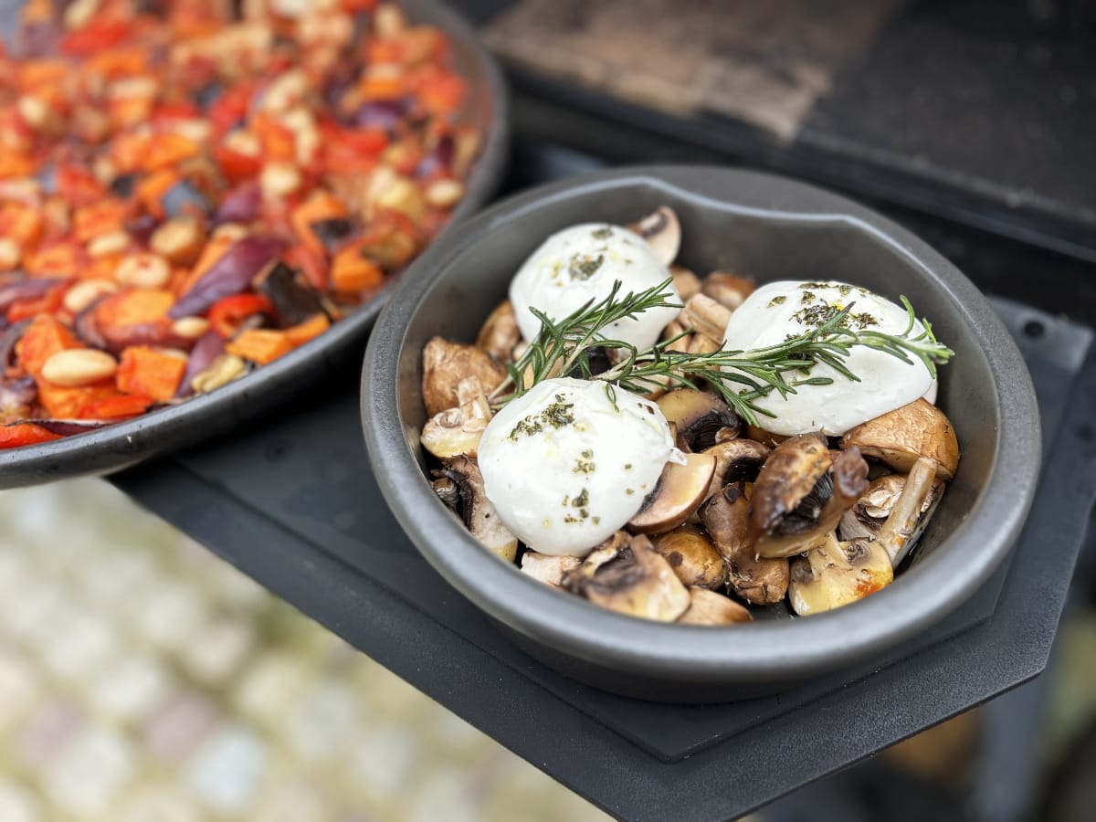 Gegrillte Champignons mit Mozzarella und Rosmarin, dazu buntes Ofengemüse in einer Gusseisenpfanne serviert.